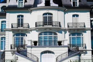 Small white apartment building with metal railings; investing in rental property is one way to make money fast