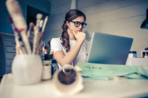 Worried woman seated at desk looking at laptop