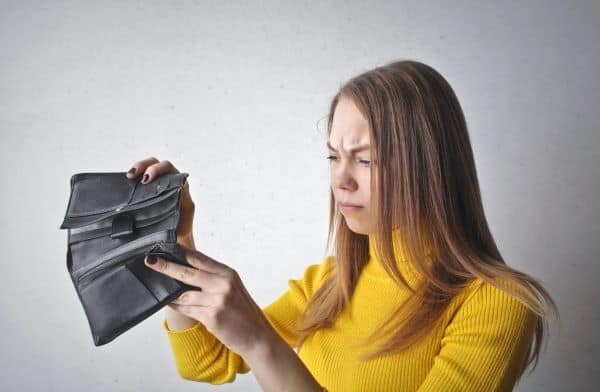 Low income budget, woman looking into empty wallet